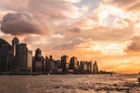 Capture of Hong Kong's skyline at sunset with dramatic clouds and waterfront view.