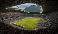 A vibrant football match at Estadio BBVA with a backdrop of Cerro de la Silla, Monterrey.