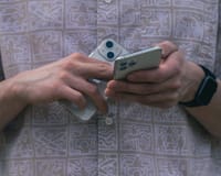 Detail of hands holding two smartphones, showcasing modern technology usage.