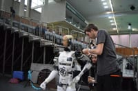 Technician working on humanoid robot at a tech exhibition in Guimaraes, Portugal.