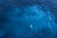 Capture of vibrant blue ocean waters with swirling patterns, viewed from above.