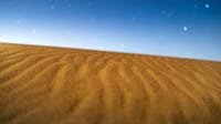 A serene landscape of desert dunes with a clear night sky full of stars, showcasing nature's vast emptiness.