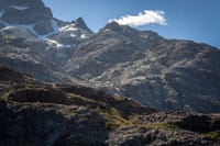 Breathtaking view of rugged mountains with snow patches under a bright blue sky.