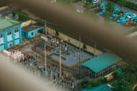 An overhead view of a city electrical substation with surrounding infrastructure.