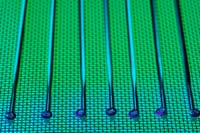 Vivid and detailed close-up of a patterned silicon wafer with vibrant green and blue colors.