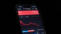Close-up of a smartphone showing a stock market chart with financial data and analytics.