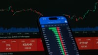 Smartphone with stock market data in front of financial chart.