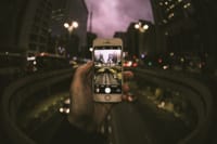 A dynamic cityscape captured through a smartphone, showcasing urban life at dusk.