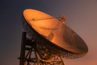 A striking satellite dish basking in golden hour light, capturing signals from space.