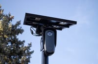A solar-powered outdoor surveillance camera mounted on a pole, capturing clear day images.