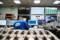 An engineer monitors multiple screens in an industrial control room, ensuring smooth operations.
