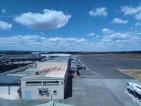 Aerial view of a sunny airport with runway and terminal buildings under blue sky.