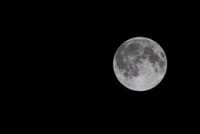A full moon shines bright against a dark night sky, showcasing its details and craters.