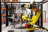 Close-up of a yellow industrial robotic arm in action at a modern manufacturing facility.