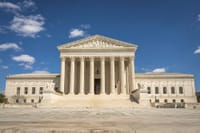 The majestic facade of the United States Supreme Court under a clear blue sky.