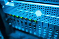 Focused view of a modern data server rack with blinking lights in a blue-lit environment.