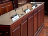 Empty courtroom desk with microphones and nameplates in a Polish court setting.