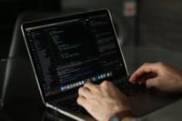 Close-up of hands coding on a laptop, focusing on programming productivity.