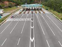 Aerial shot of an empty multi-lane toll booth on a highway surrounded by greenery.