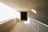 Empty hallway of modern light building with concrete walls and balcony with bright sunlight