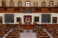 The Texas House of Representatives chamber, featuring legislative seats and historical portraits.