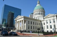 The iconic Old Courthouse with its dome in downtown St. Louis, reflecting in modern glass buildings.