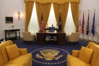 Interior of a presidential office showcasing elegant design with flags and majestic furnishings.