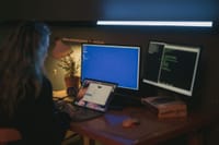 Woman using multiple screens for cybersecurity tasks in a cozy home office