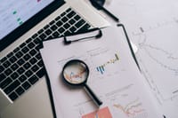 Overhead view of financial charts, laptop, and magnifying glass, ideal for business analysis themes.