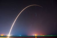 A breathtaking shot of a rocket launch, creating a vivid trail under a starry night sky.