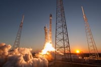 Low angle of modern rocket taking off into cloudless sky during beautiful sunset over space factory