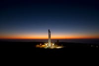 A powerful rocket stands ready on its launch pad against a stunning twilight sky.