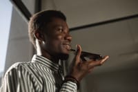 Smiling African American man talking on smartphone in an indoor setting.