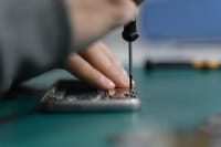 Detailed shot of smartphone repair with a screwdriver and hand close-up.