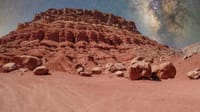 Stunning red rock formations under the Milky Way, resembling a Martian terrain.