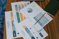 Overhead view of project management documents and charts on a desk with a pencil.