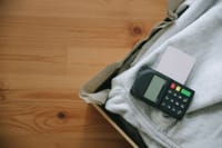 Close-up of payment terminal with credit card on grey clothing, ideal for retail concepts.