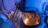 Close-up of a woman in a reflective moment with a space helmet, conveying emotion and futuristic themes.