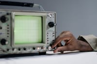 A person adjusts settings on a vintage oscilloscope in a studio environment.