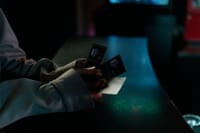 Moody image of a person holding cinema tickets at night, highlighting anticipation of a movie night.