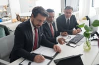 Three professionals collaborating on business plans in modern office.