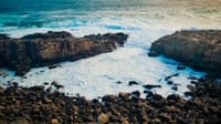 Dramatic waves crash against the rocky shoreline of Plettenberg Bay, South Africa.