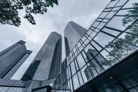 Modern skyscrapers with glass facades reflecting the urban skyline on an overcast day.