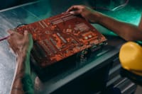 Close-up of a technician working on a circuit board in an industrial setting.