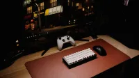 Primer plano de una configuración de escritorio de juegos con teclado, controlador y monitor por la noche.