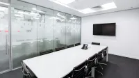 Sleek, minimalist conference room with glass walls, long table, and office chairs.