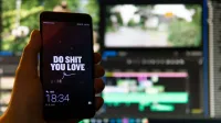Close-up of a smartphone displaying an inspirational message against a video editing background.