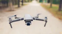A sleek, modern drone captured flying outdoors in a serene park setting.
