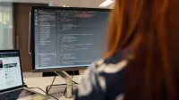 Una ingeniera trabaja en código en un entorno de oficina contemporáneo, mostrando el desarrollo de software.