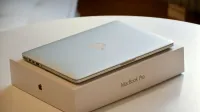 Una computadora portátil MacBook Pro colocada en su empaque original sobre una mesa interior blanca.